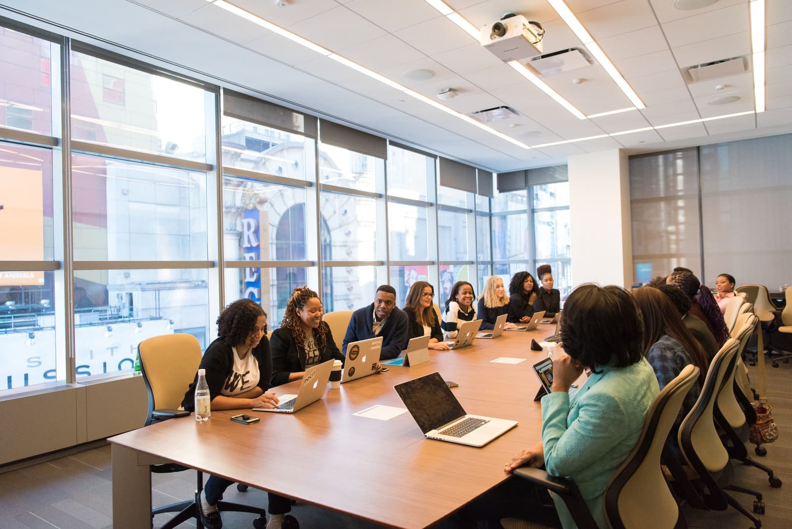 A diverse team working together with laptops around a long conference table in a bright, modern office